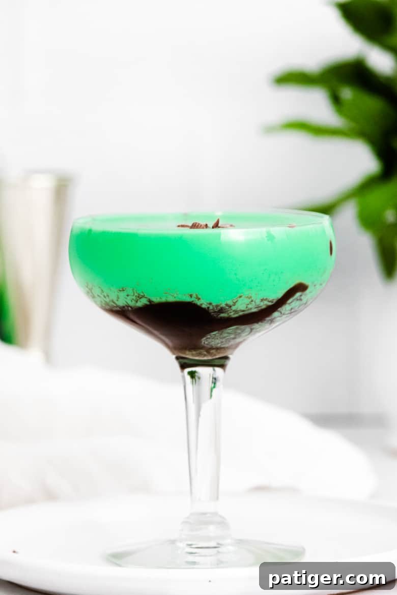 Emerald Elixir 4 Bright green Grasshopper drink in a cocktail glass drizzled with chocolate syrup and topped with chocolate shavings