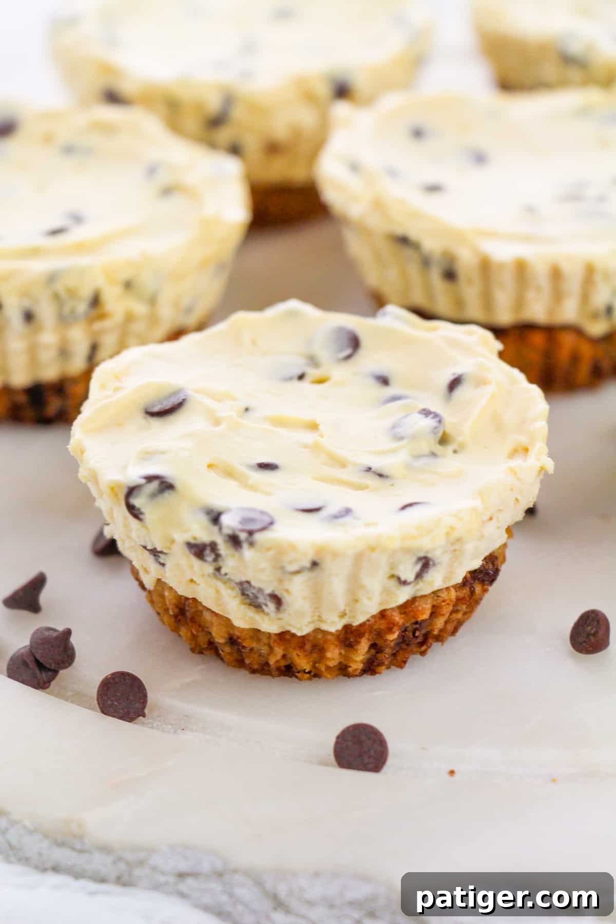 Delightful Mini Chocolate Chip Cookie Dough Cheesecake Cups arranged on a pristine white plate, garnished with a sprinkle of mini chocolate chips, showcasing their individual charm and delicious appeal.