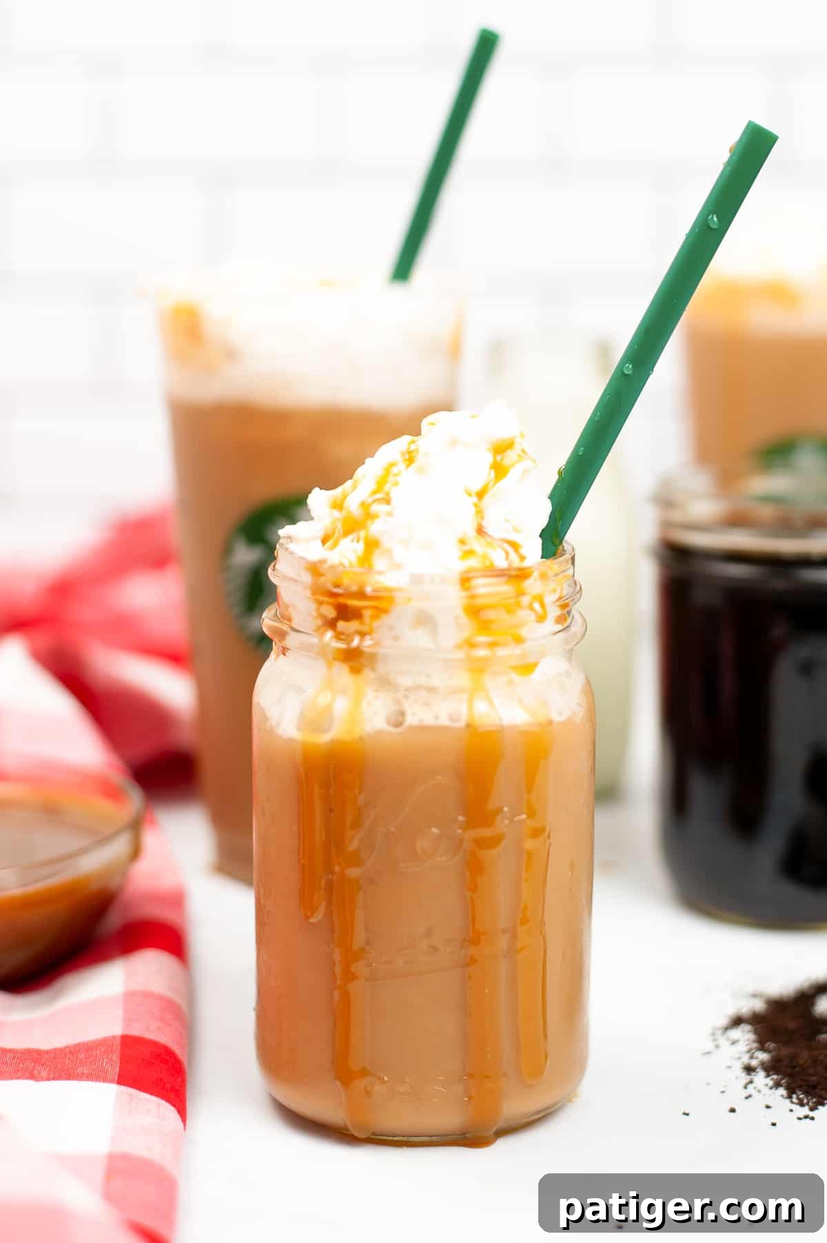 Caramel Frappuccino topped with whipped cream and caramel drizzle served in a mason jar with green straw