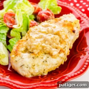 Smothered Chicken Breast served with salad on a red plate.