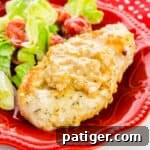 Smothered Chicken Breast served with salad on a red plate.