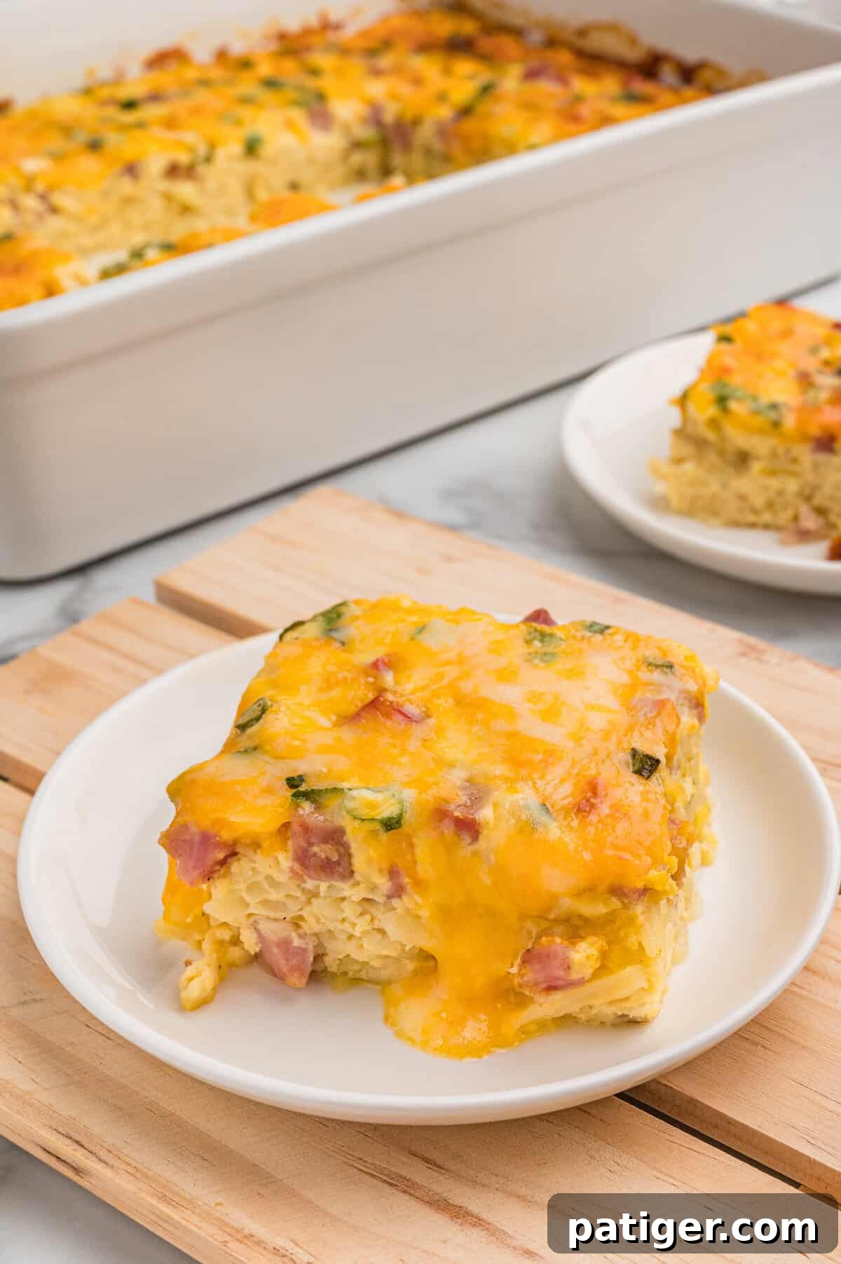 A slice of farmers casserole plated in front of the baking dish.
