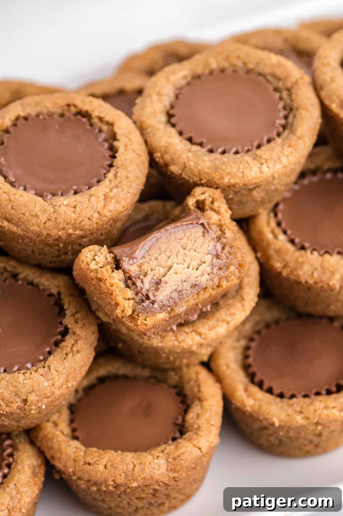 Peanut Butter Cup Cookies with a mini reese's cup in the center. One had bite taken out of it to show inside of reese's peanut butter cup.