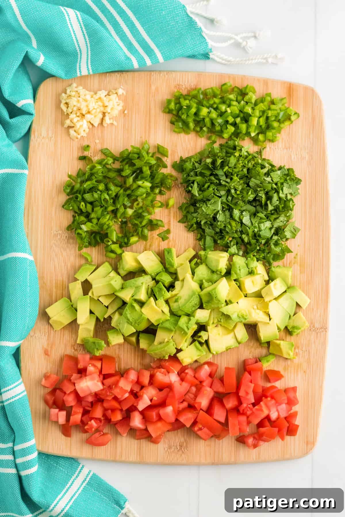 Garlic, scallions, jalapeno, cilantro avocado, and tomato chopped on cutting board