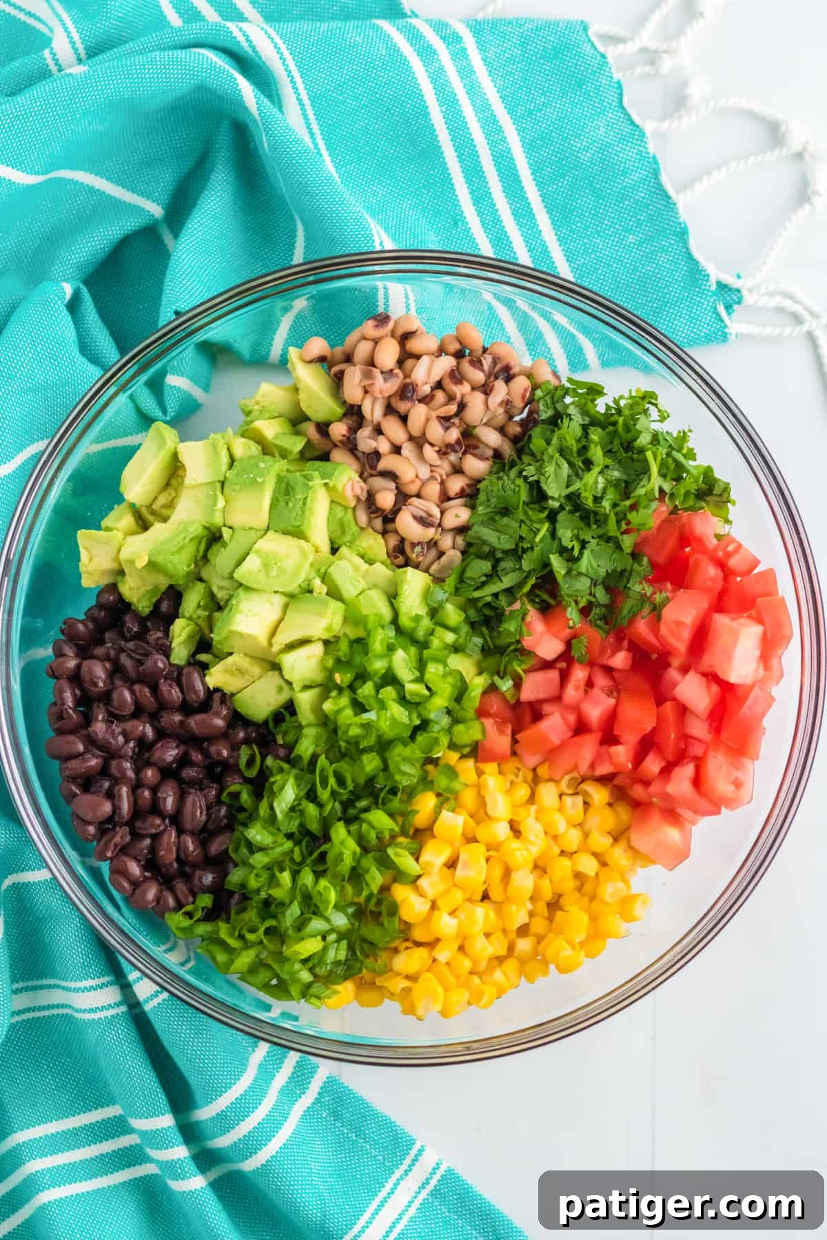 Corn, black beans, black eyed peas, and chopped avocado, jalapeño, scallions, tomatoes, and cilantro in a large mixing bowl.