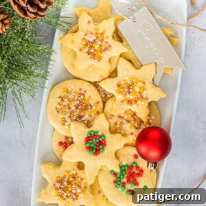 Christmas Shortbread Cookies cut in snowflake and circle shapes, and decorated with holiday sprinkles.