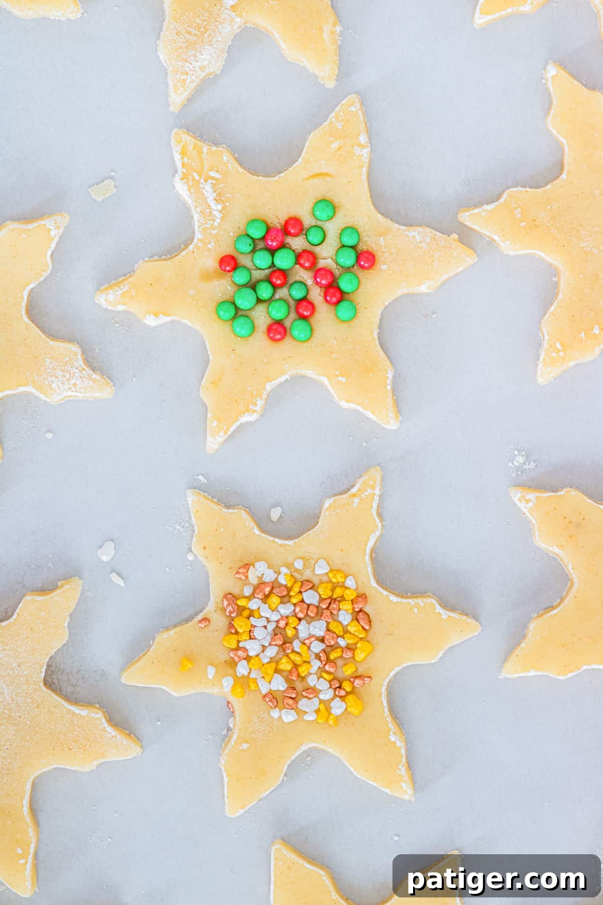 Snowflake shortbread cookies with sprinkles on top on lined baking sheet