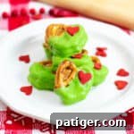 Grinch Pretzel Bites on white plate with red heart sprinkles sprinkled around them