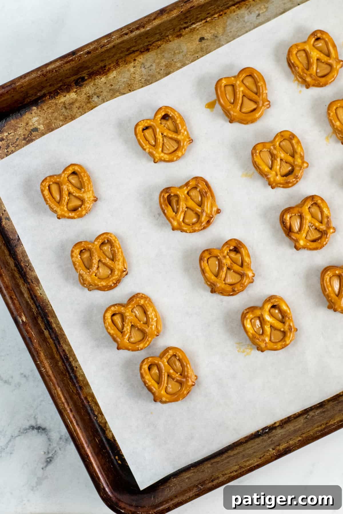 mini pretzels on baking sheet topped with melted caramel and another mini pretzel