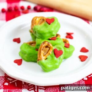 Grinch Pretzel Bites on white plate with red heart sprinkles sprinkled around them