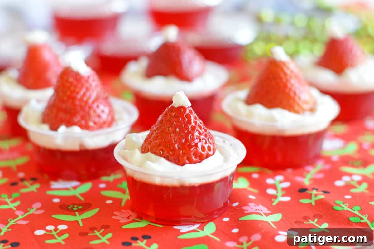 Strawberry Santa Hat Jello Shots made with strawberry jello, whipped cream, and fresh strawberries, arranged festively for a Christmas party.