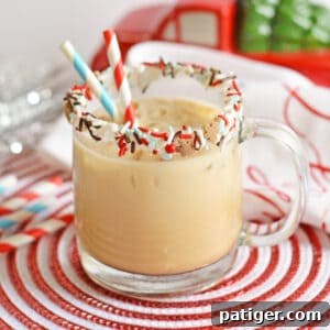 Gingerbread cocktail with vodka and kahlua in glass mug with sprinkles on rim and two paper straws. Christmas decor is in the background.