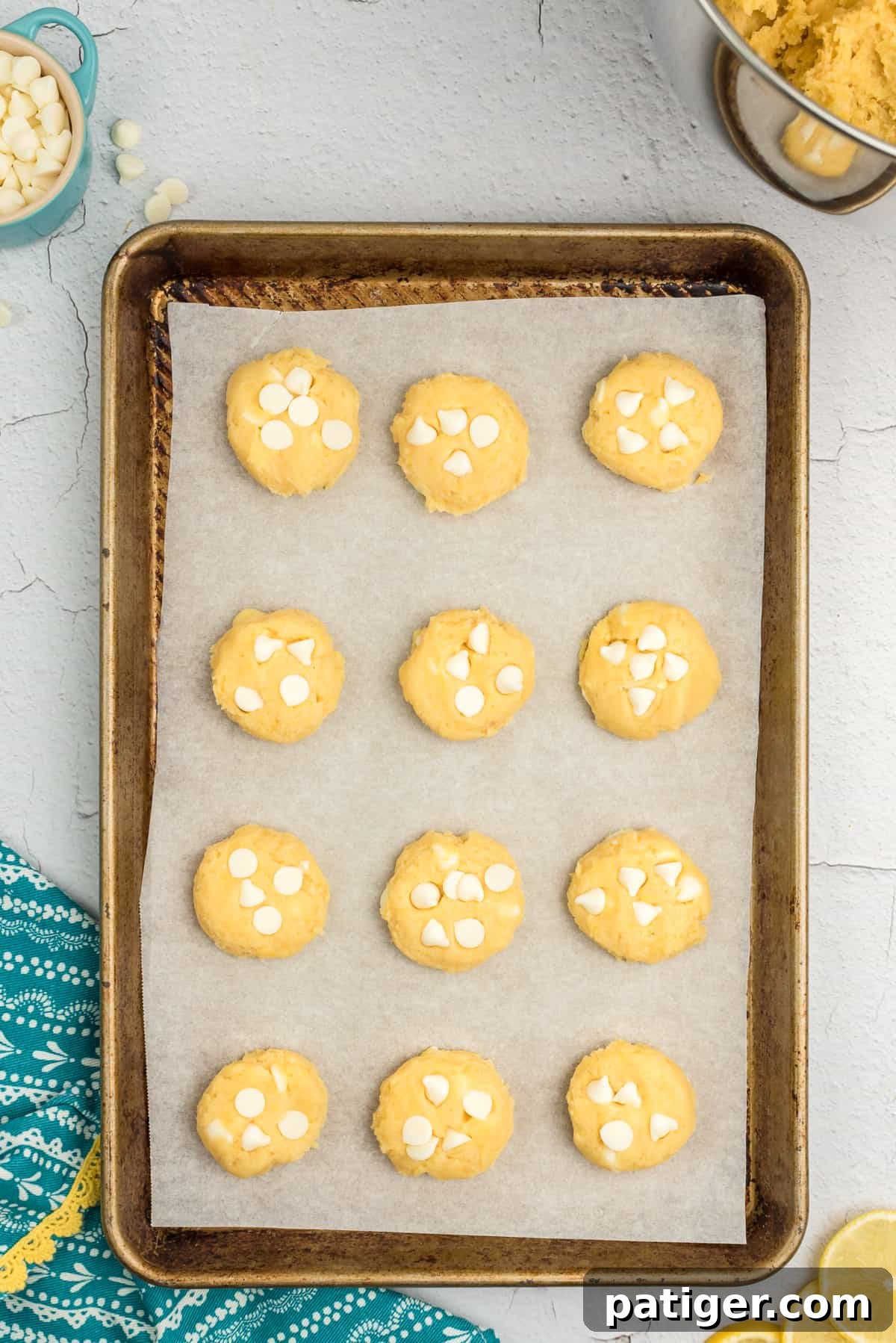 Lemon pudding mix cookie dough with white chocolate chips on a lined baking sheet, ready for baking.