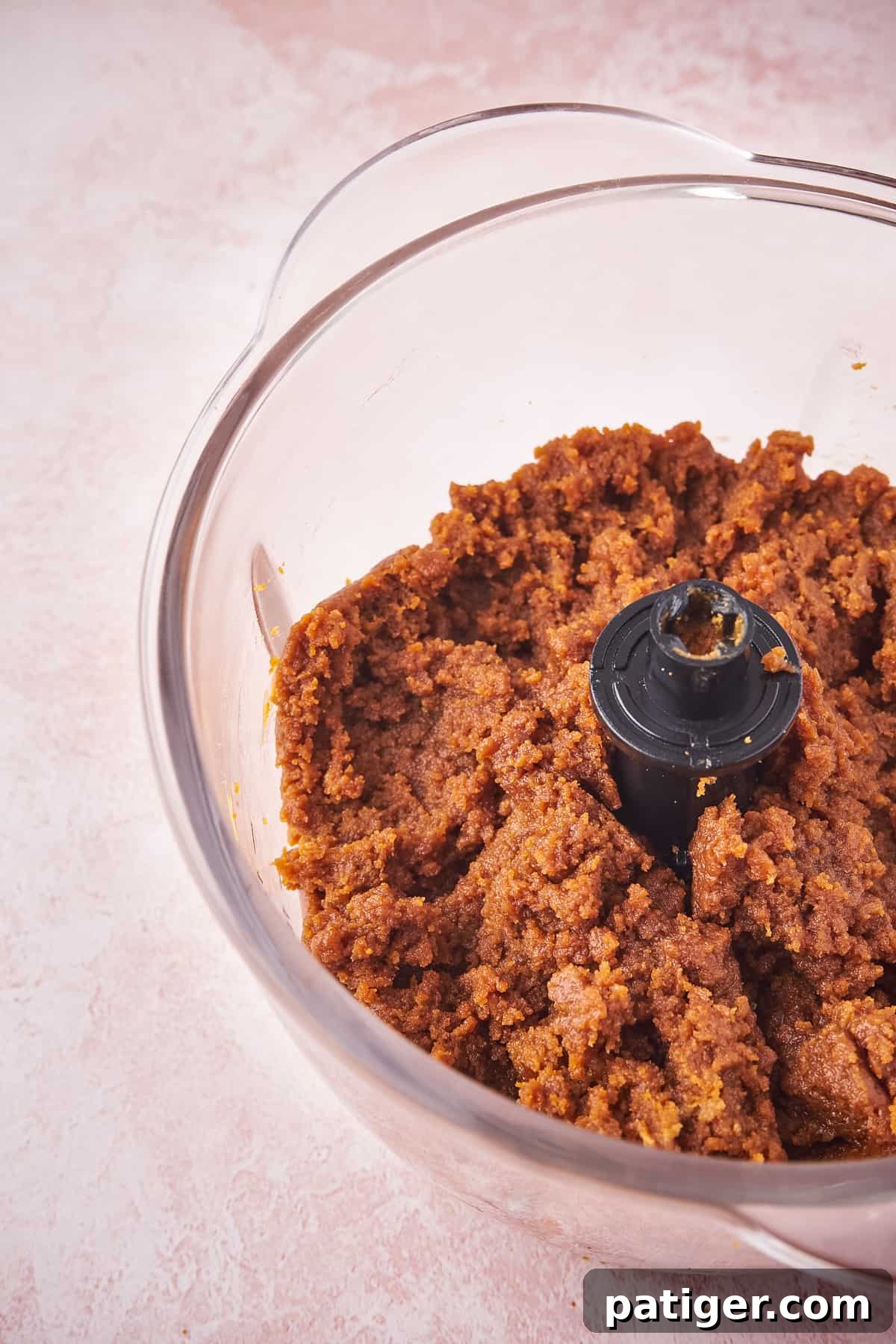 Biscoff truffle ingredients – crushed cookies, cookie butter, and cream cheese – being processed together into a thick dough.
