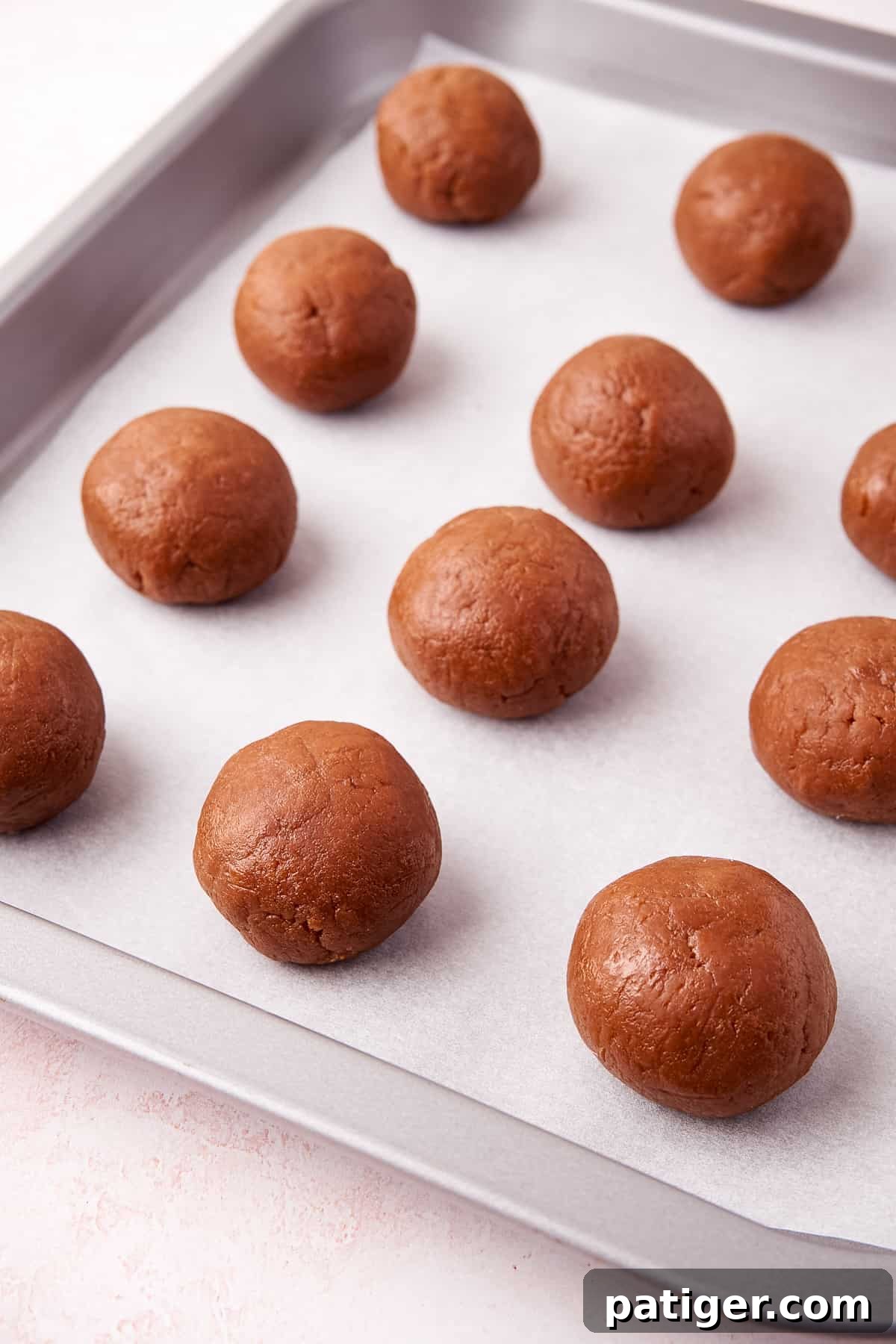 Neatly rolled balls of Biscoff cookie truffle mixture arranged on a parchment-lined baking sheet, ready for chilling.