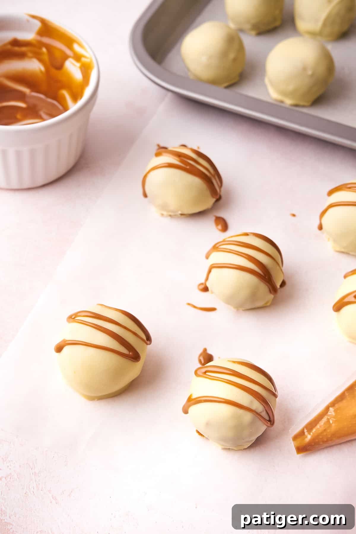 Hands carefully drizzling melted Biscoff cookie butter over the tops of freshly dipped no-bake truffles for decoration.