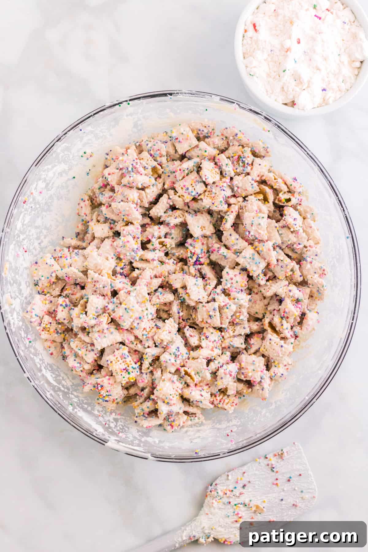 Large glass bowl with chex coated in white chocolate and sprinkles