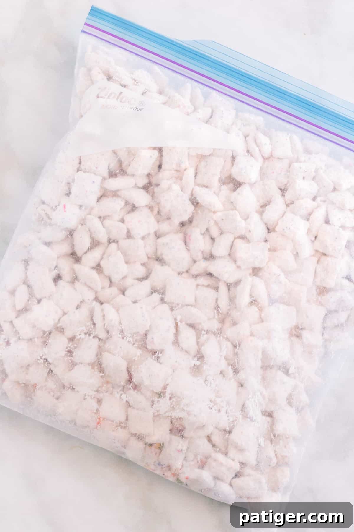 Large gallon size ziplock baggie filled with powdered sugar, funfetti mix, and white chocolate coated chex cereal