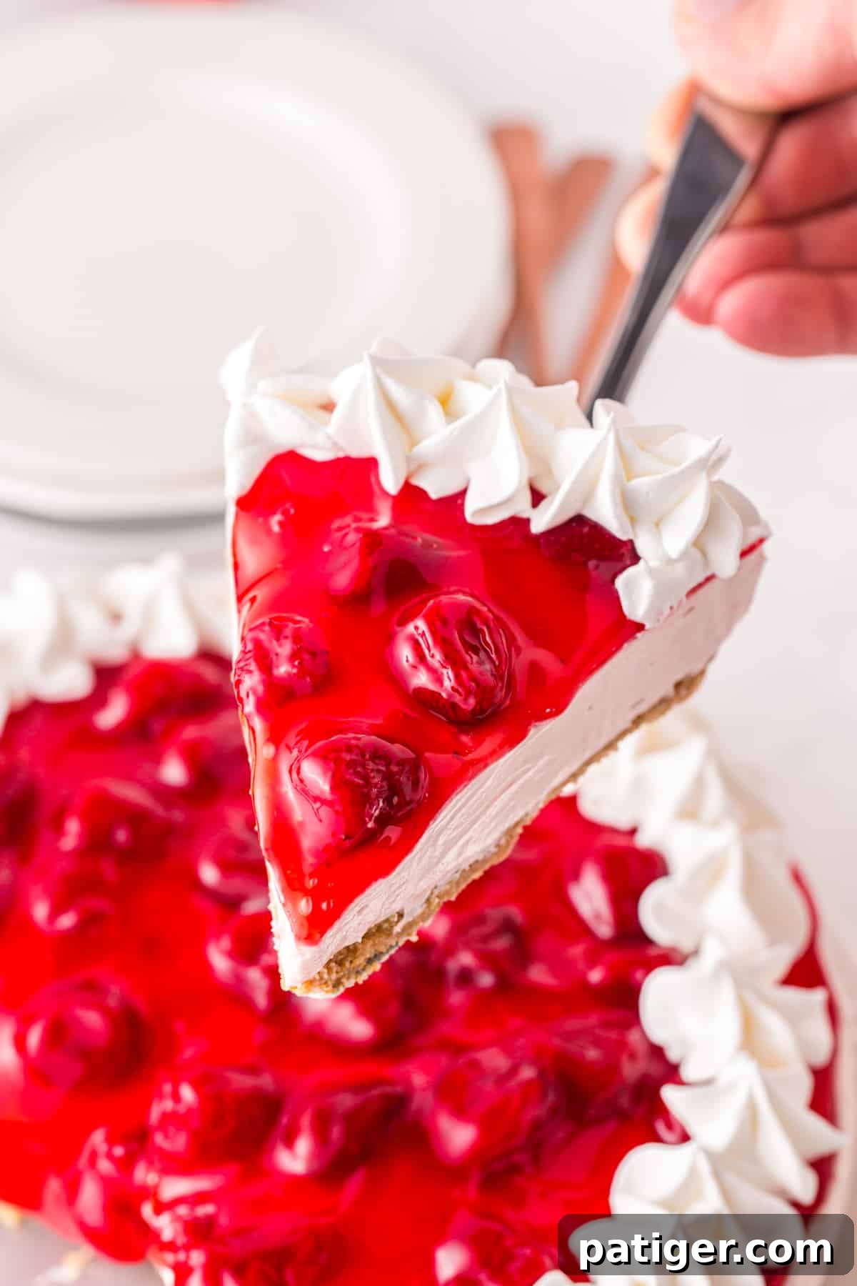 Slice of no bake strawberry cheesecake being lifted and removed from the cake.