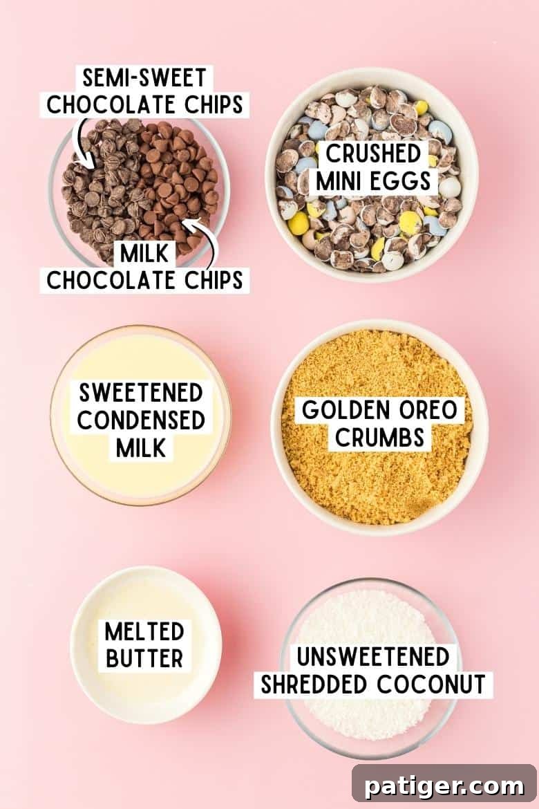 Milk chocolate chips, semi-sweet chocolate chips, crushed mini eggs, golden oreo crumbs, sweetened condensed milk, melted butter. unsweetened shredded coconut in bowls on pink surface.