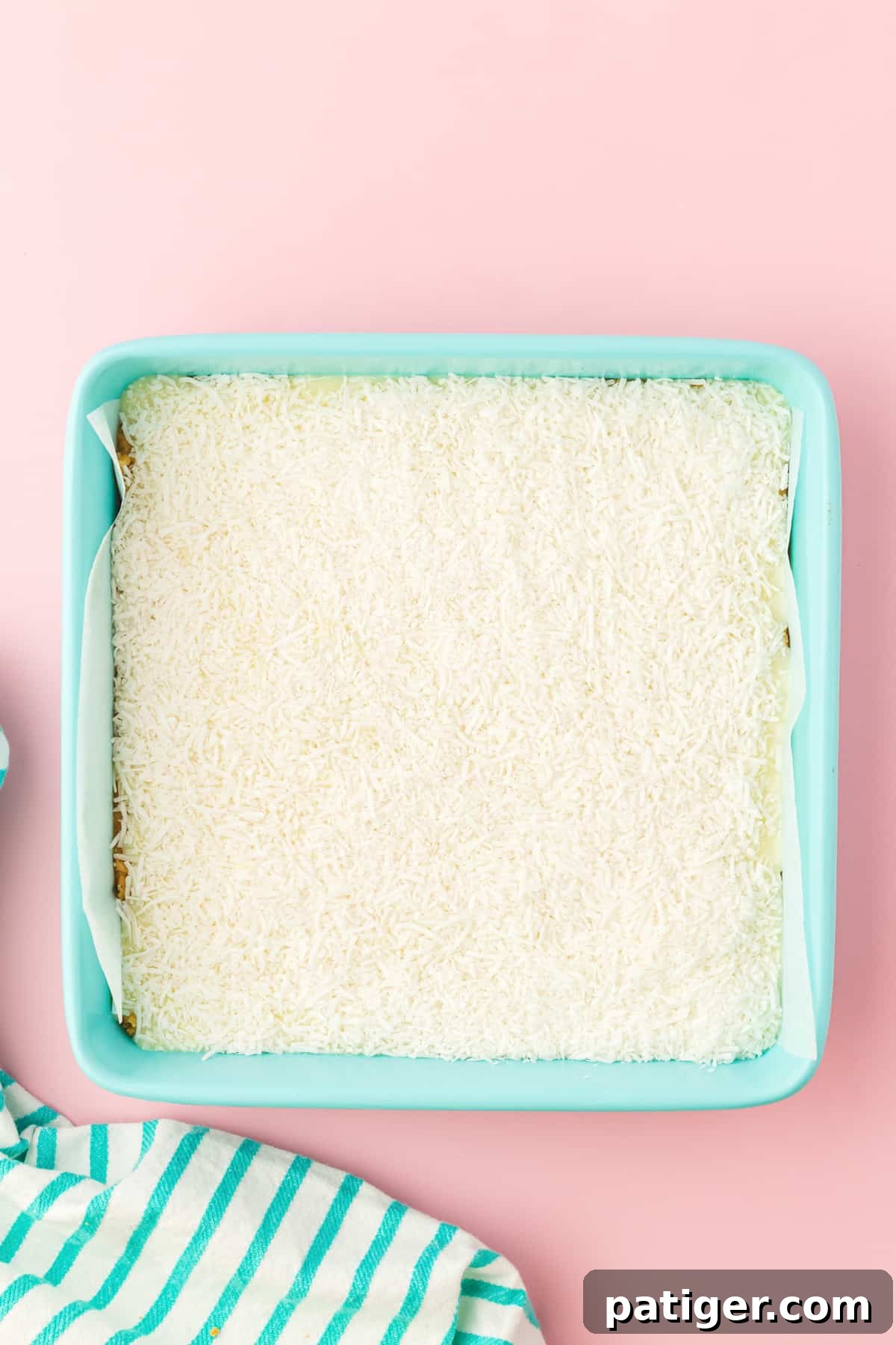 Shredded coconut in an even layer in square baking pan.
