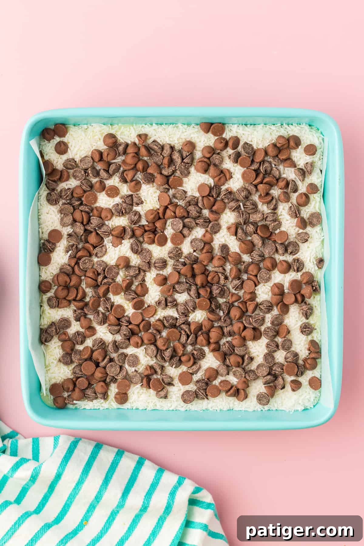 Square casserole dish with shredded coconut topped with chocolate chips.