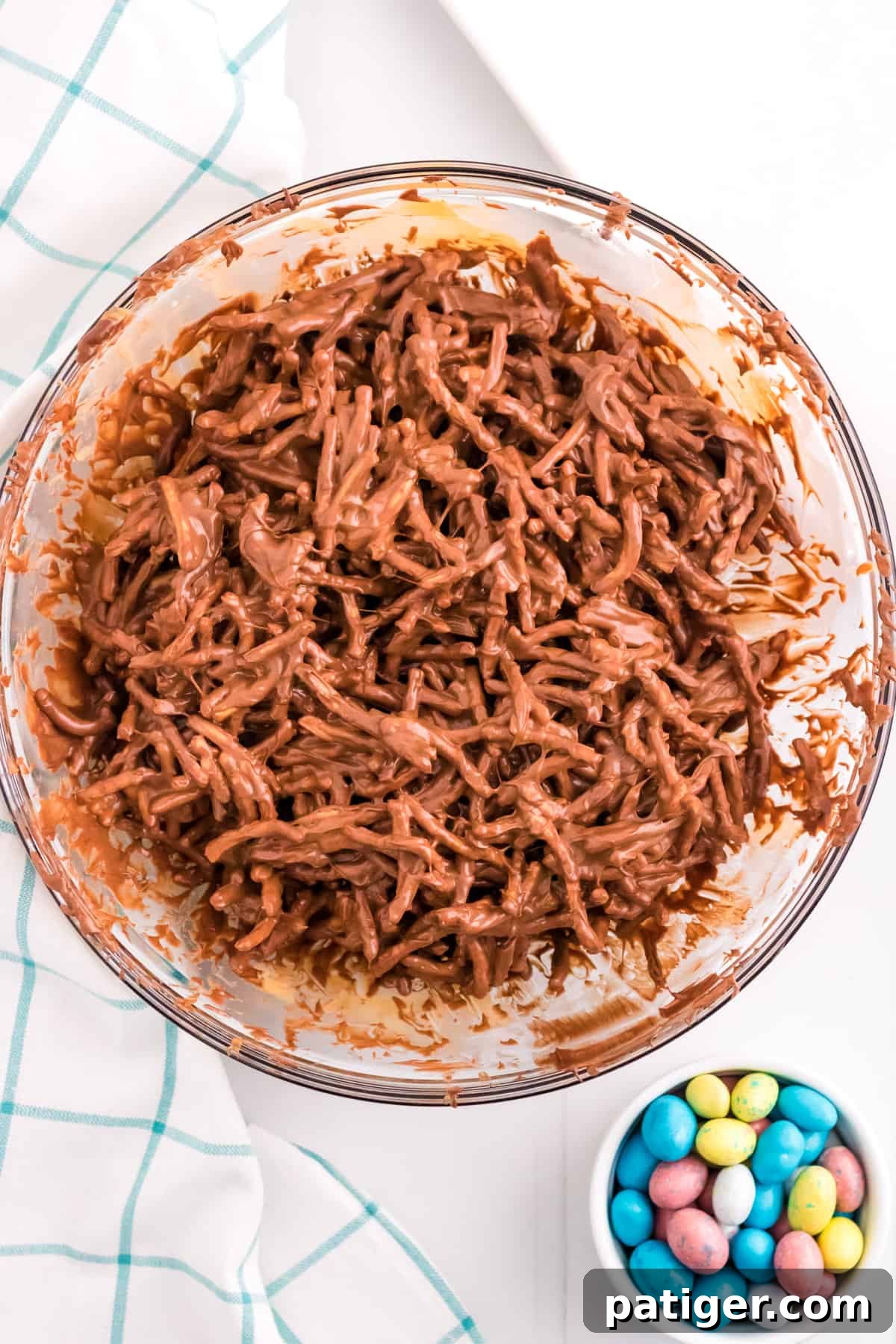 Chocolate chow mein noodles in mixing bowl with egg candies next to it.