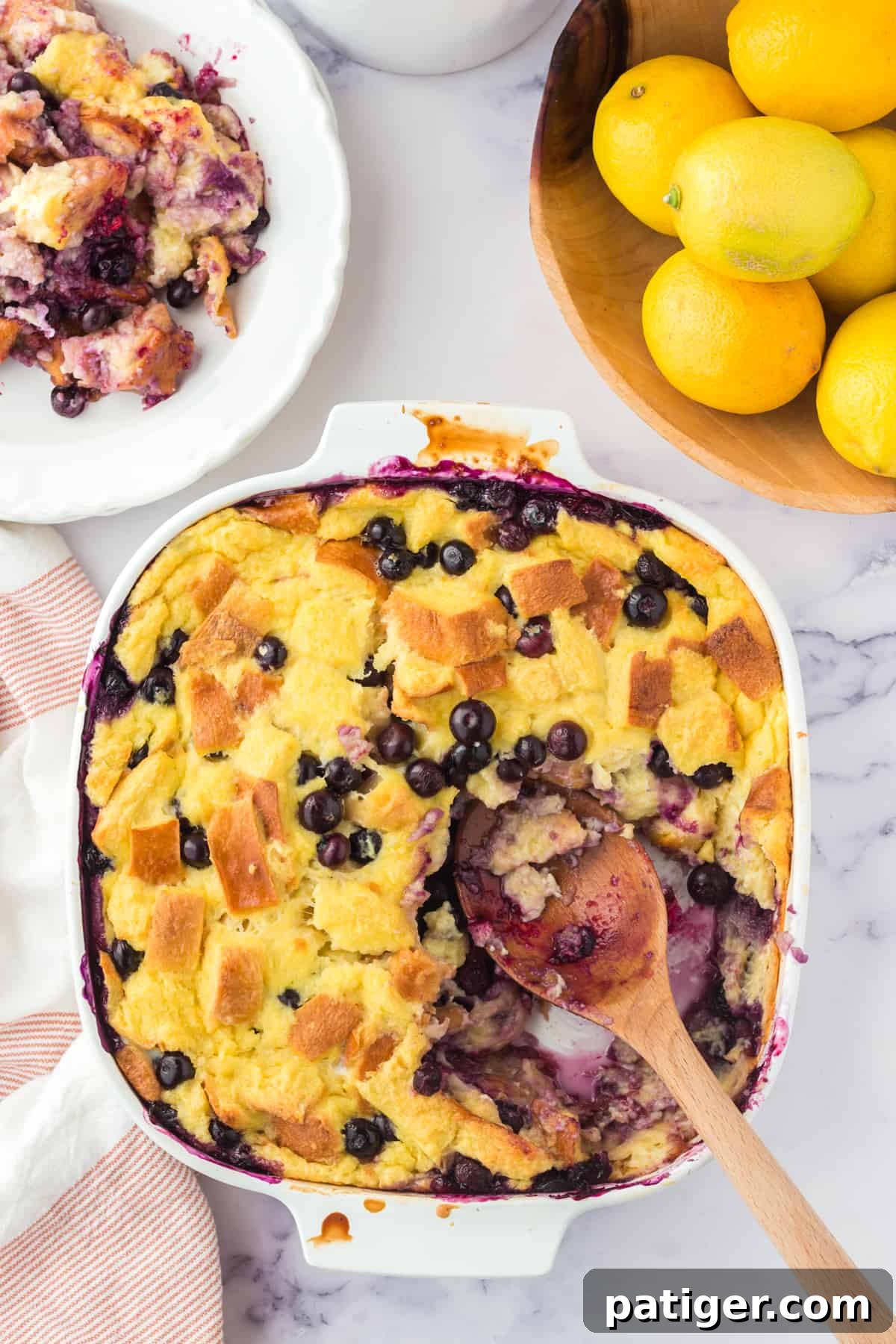 Lemon Blueberry Bread pudding with wooden serving spoon resting in dish after several servings were removed.