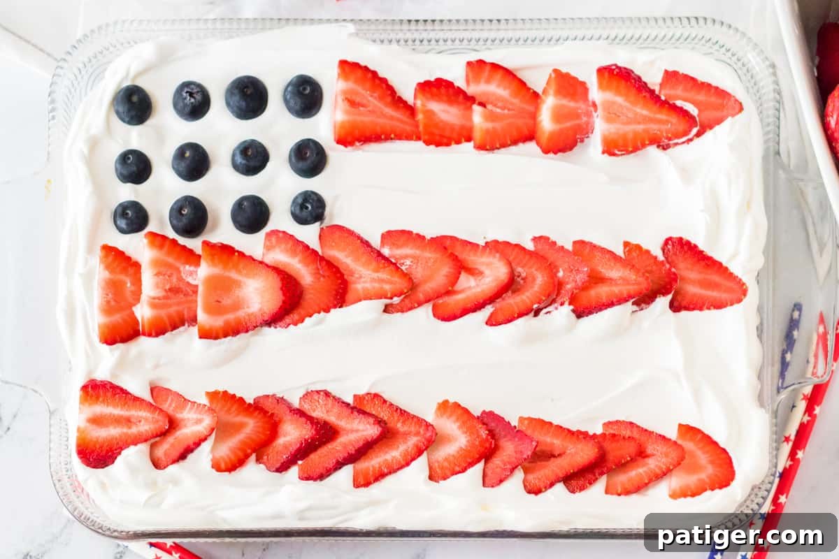 Sheet cake topped with sliced strawberries and blueberries to resemble a flag.