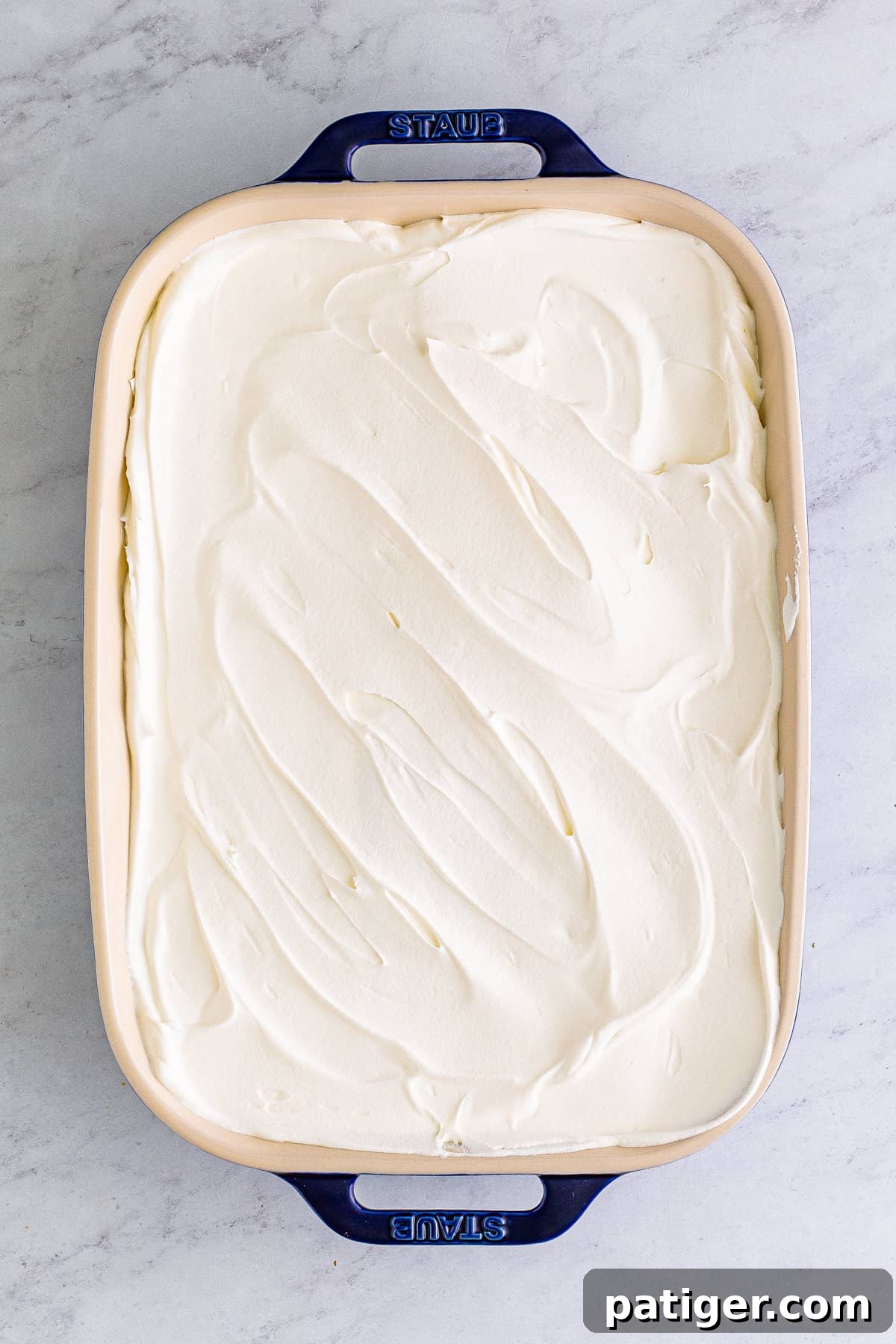 Casserole dish with layered dessert topped with cool whip.