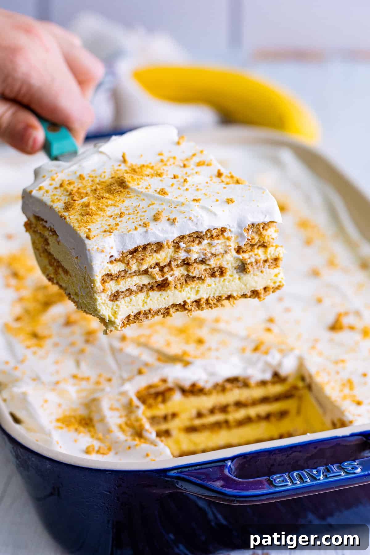 Spatula lifting a slice of banana cream icebox cake out of pan.