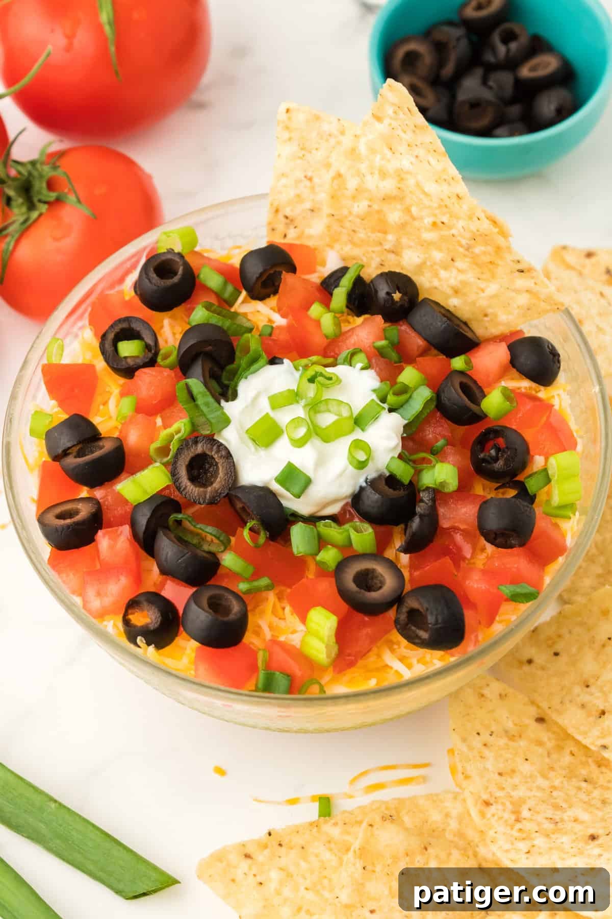 An earlier version of the layered taco dip, presented in a round bowl and served with a variety of tortilla chips, showcasing its delicious appeal.