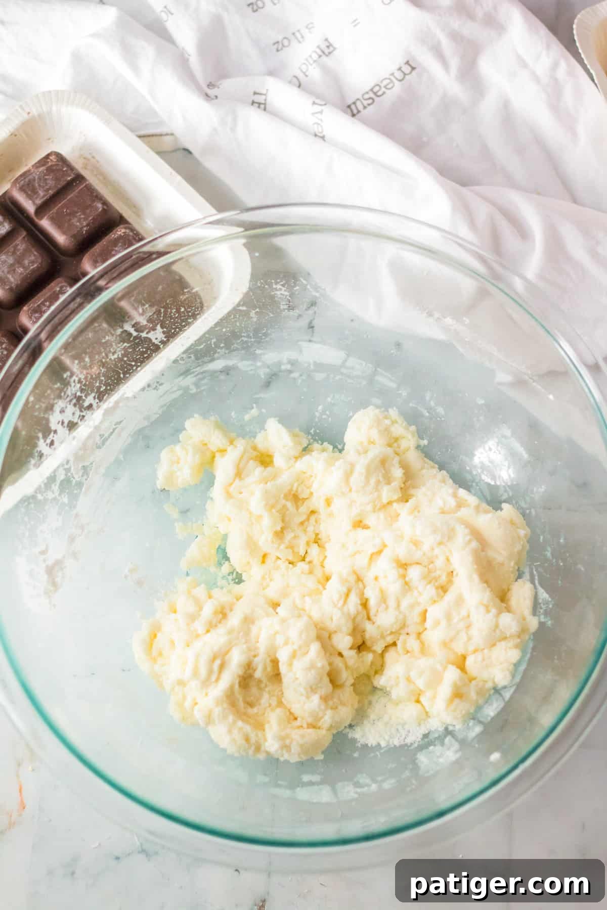 A perfectly stiff peppermint patty dough, formed from sweetened condensed milk, peppermint extract, and confectioners' sugar, rests in a mixing bowl, ready for shaping.