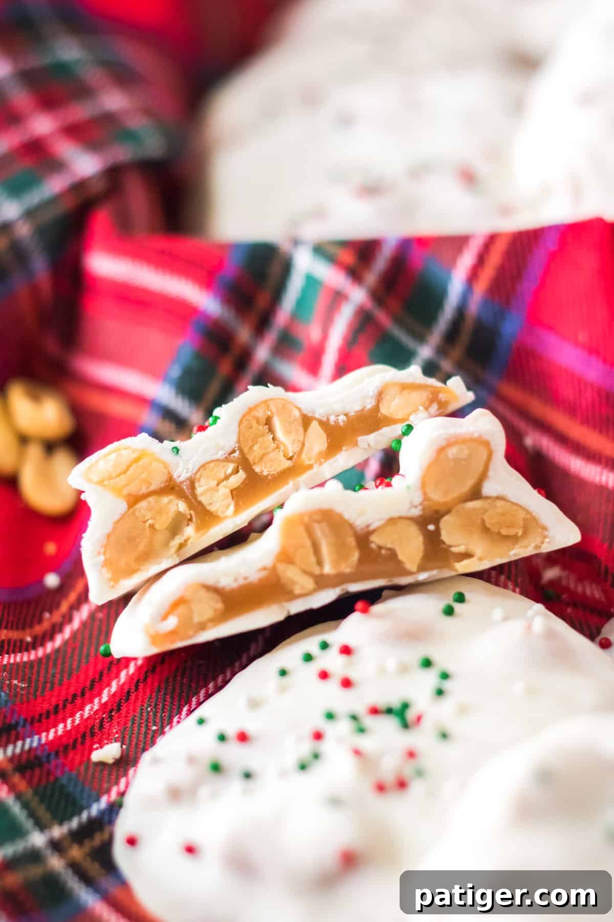 A close-up of Polar Bear Paws candy arranged on a red plaid cloth. One candy is cut open, showcasing the rich caramel and nut cluster within.
