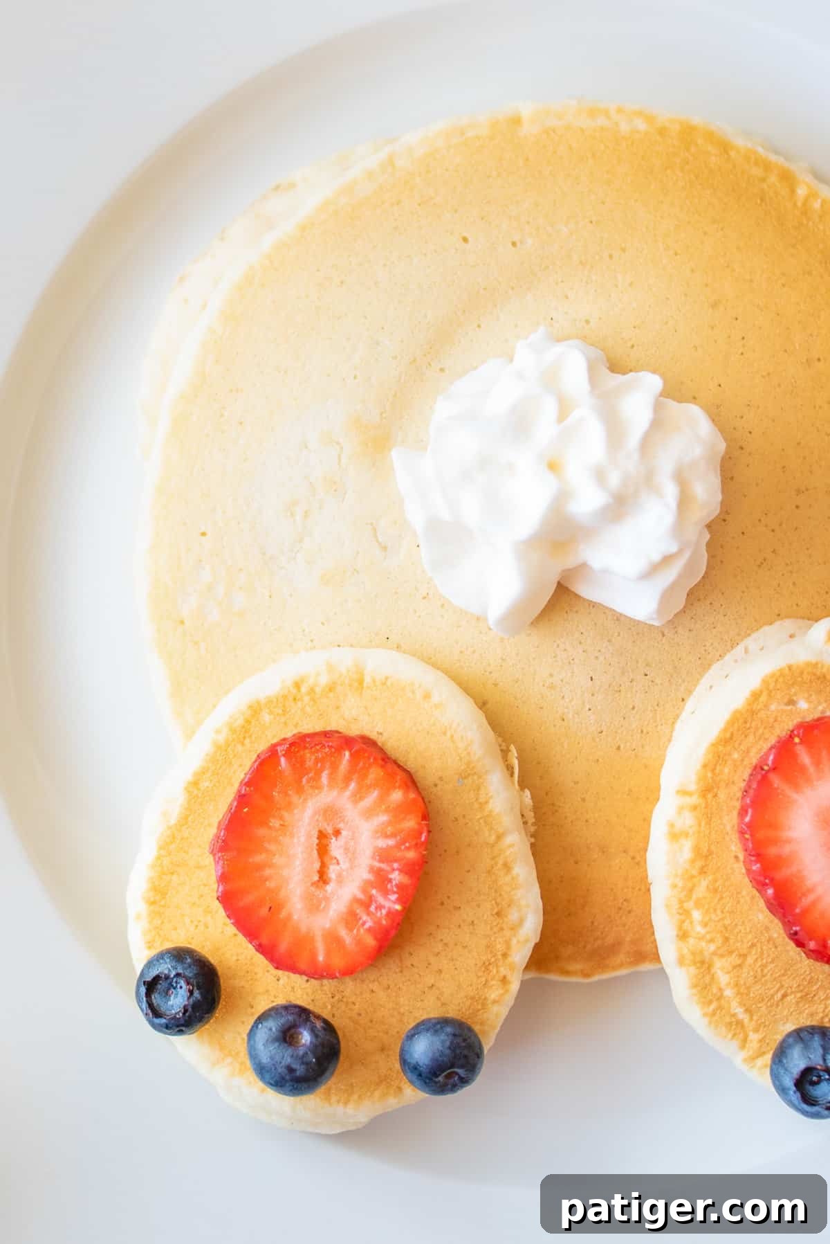 Cottontail Pancakes 7 Close up of pancakes topped with strawberry slices, whipped cream, and blueberries arranged to look like an Easter bunny's butt.
