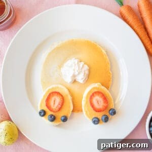 Easter pancakes topped with strawberry slices, blueberries, and whipped cream arranged to look like a bunny's butt.