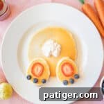 Easter pancakes topped with strawberry slices, blueberries, and whipped cream arranged to look like a bunny's butt.