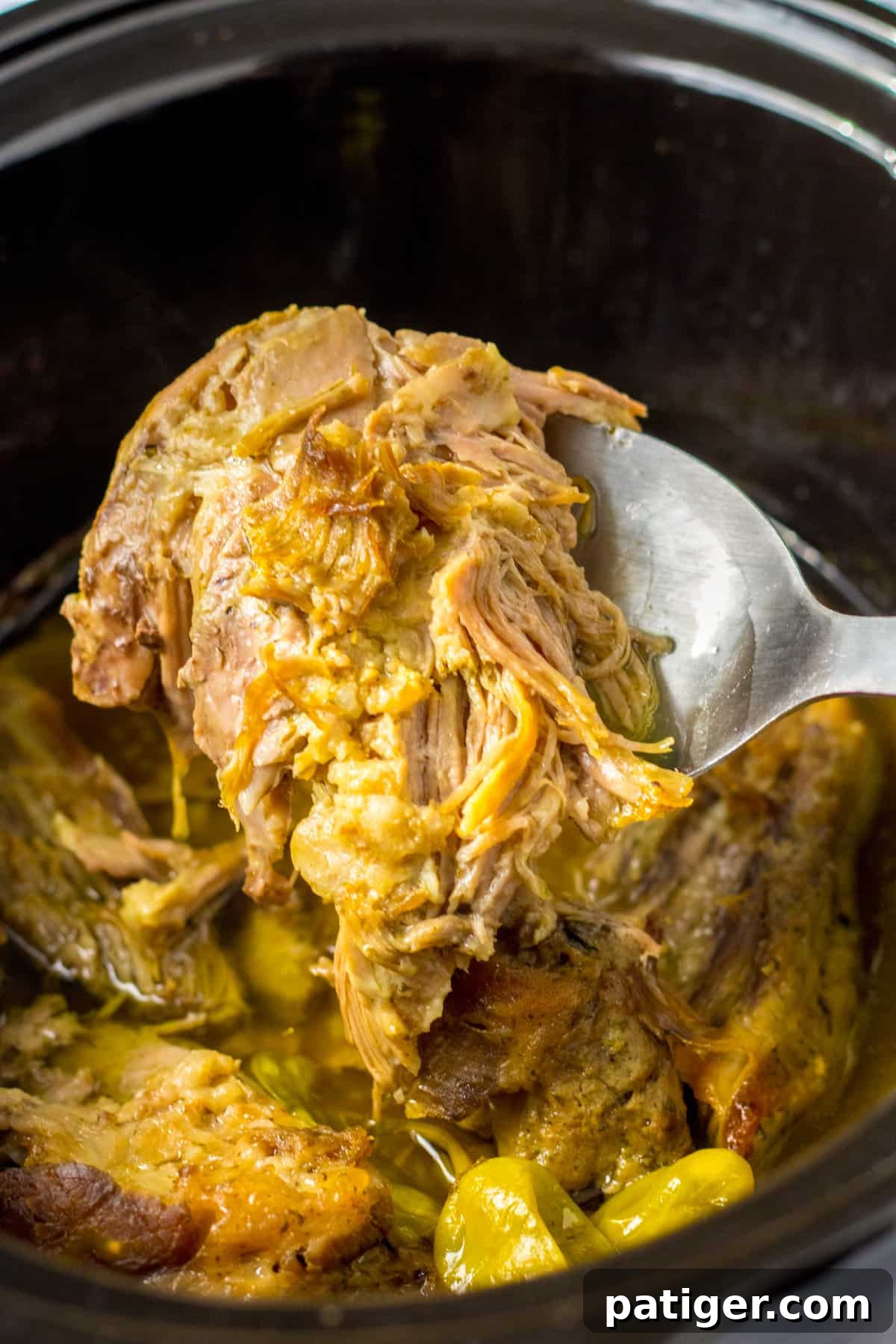 Juicy mississippi pork roast being lifted with a spoon out of the slow cooker. The meat is falling apart it is so unbelievably tender.