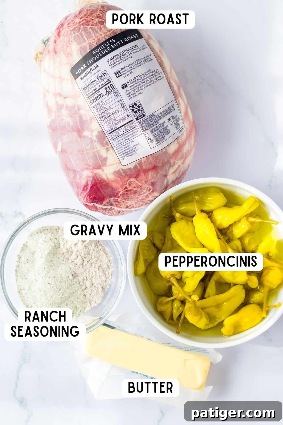 Ingredients for Mississippi Pork Roast: pork shoulder butt, pepperoncini peppers, stick of butter, ranch seasoning, and gravy mix arranged on a cutting board.