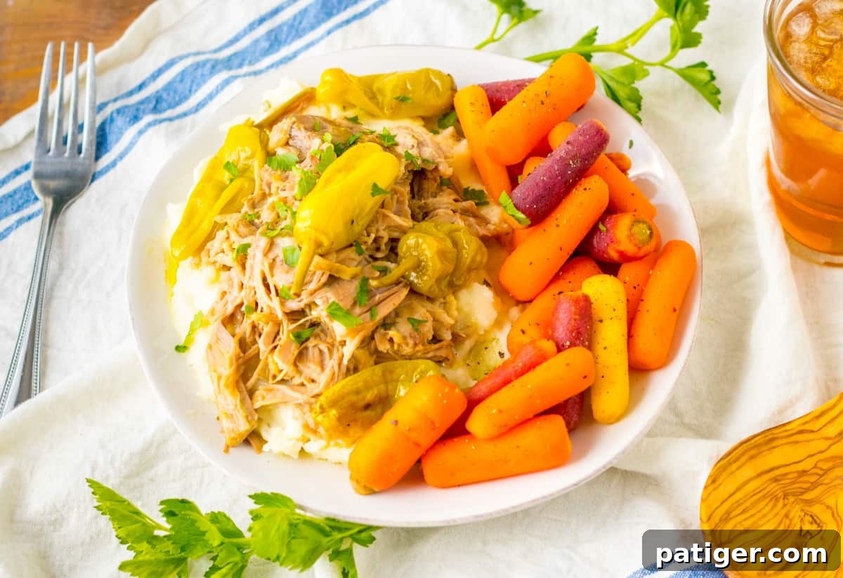 Slow cooker mississipi pork served over mashed potatoes with a side of glazed carrots. 