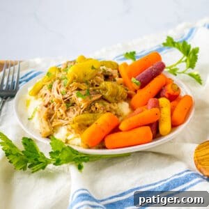 Slow cooker mississipi pork served over mashed potatoes with a side of carrots.