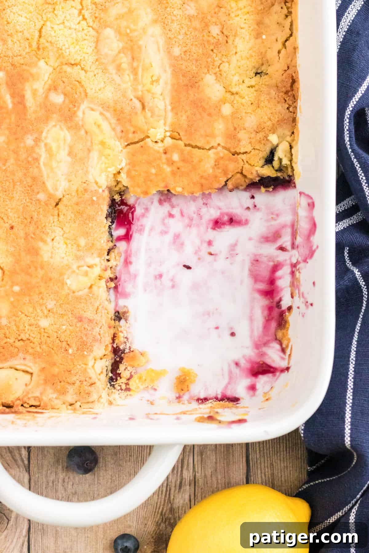 Lemon blueberry dump cake with a square serving missing from the corner, revealing the rich blueberry filling beneath the golden crust.
