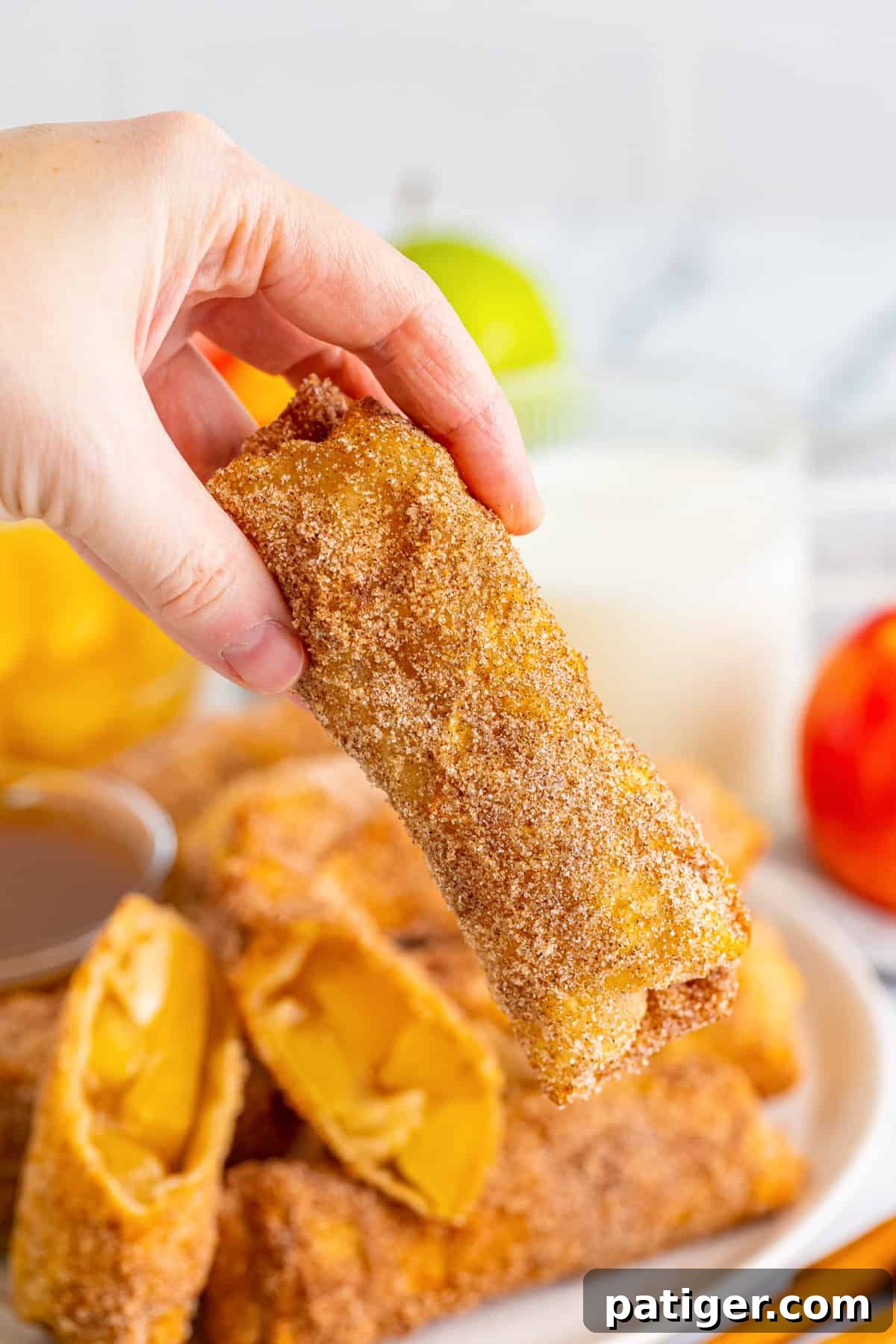 Hand holding fried apple pie egg roll.