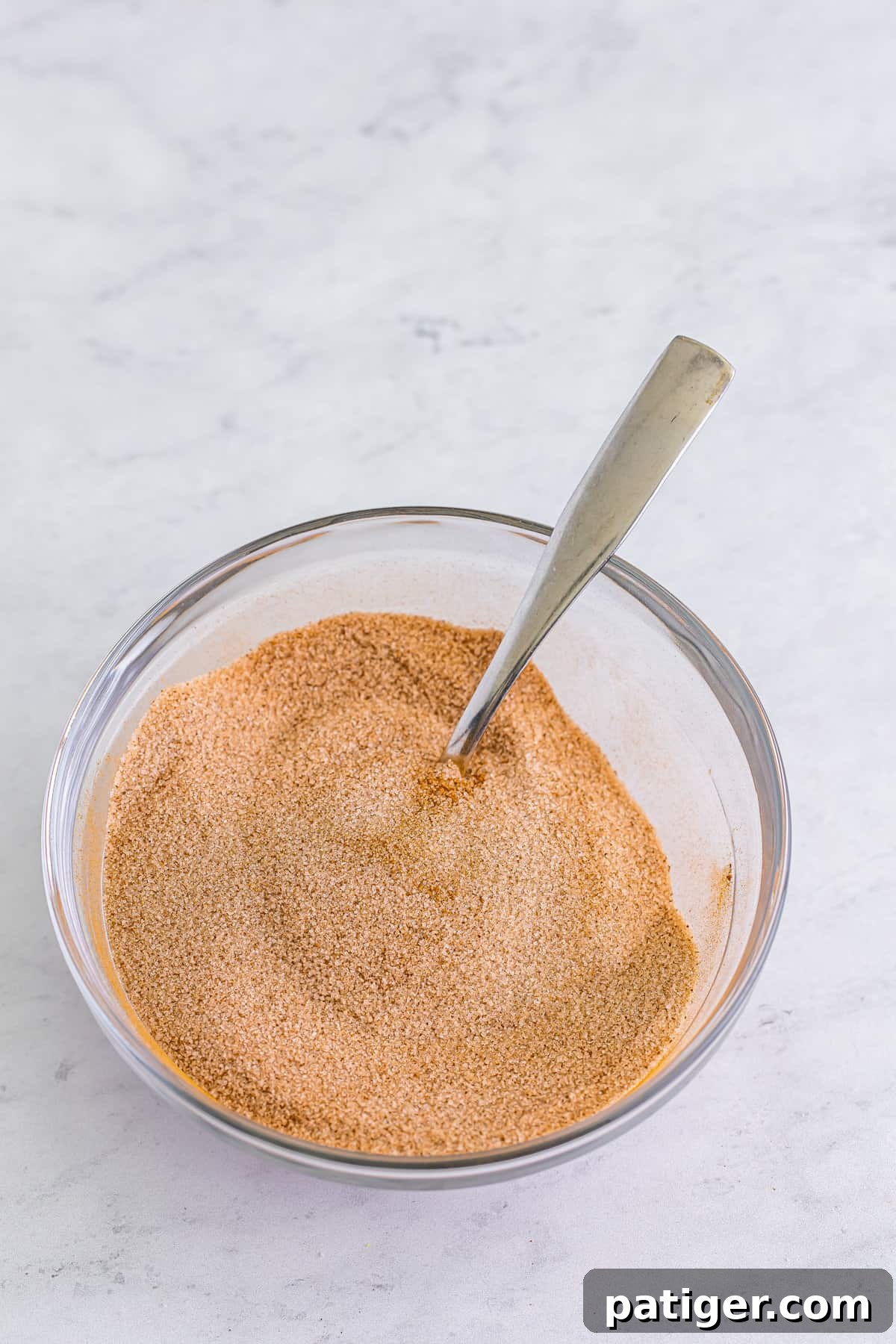 Cinnamon sugar in mixing bowl with spoon.
