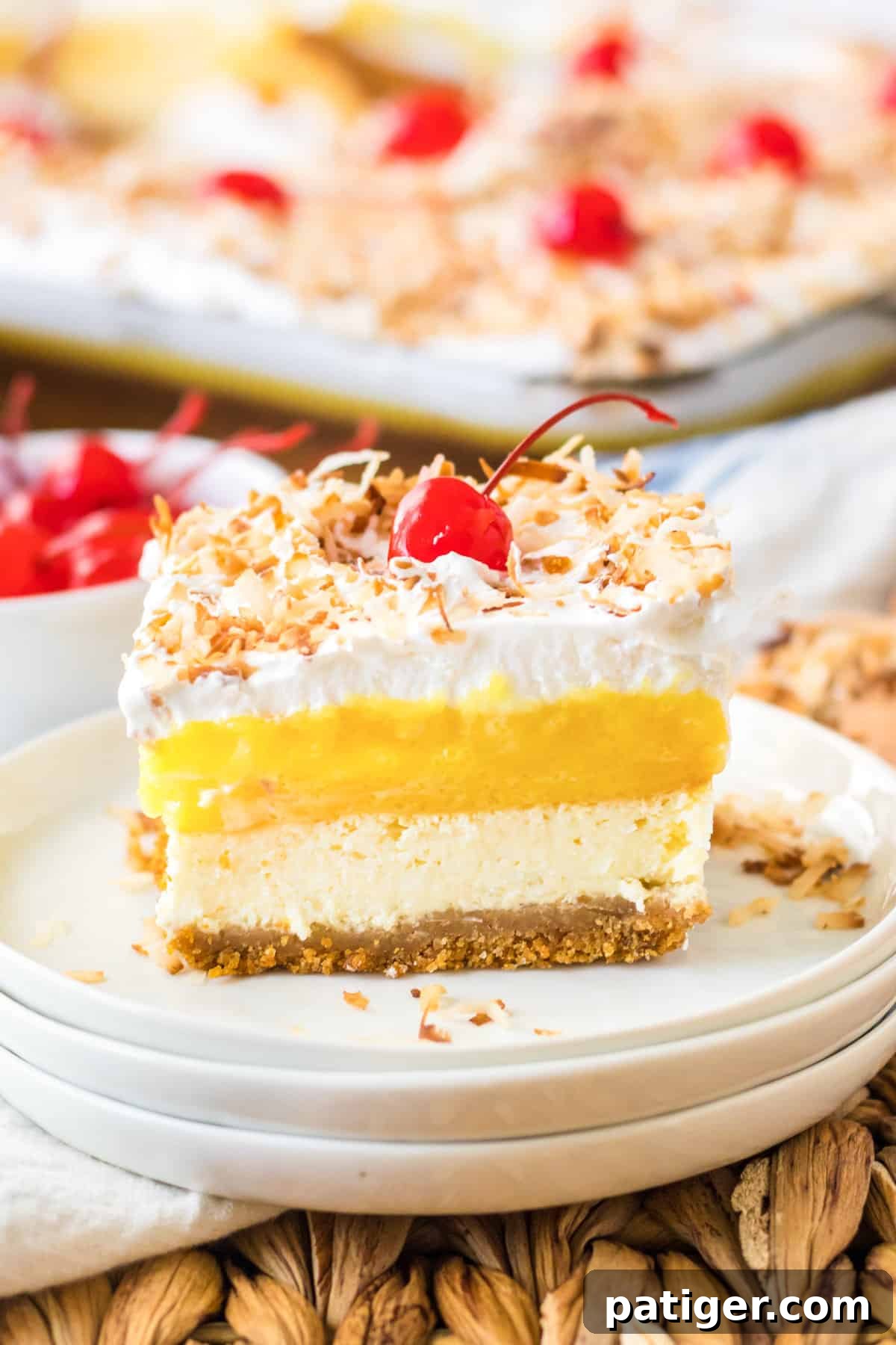 A perfectly sliced square of Pina Colada Lush dessert, served elegantly on a pristine white plate, showcasing its beautiful layers.