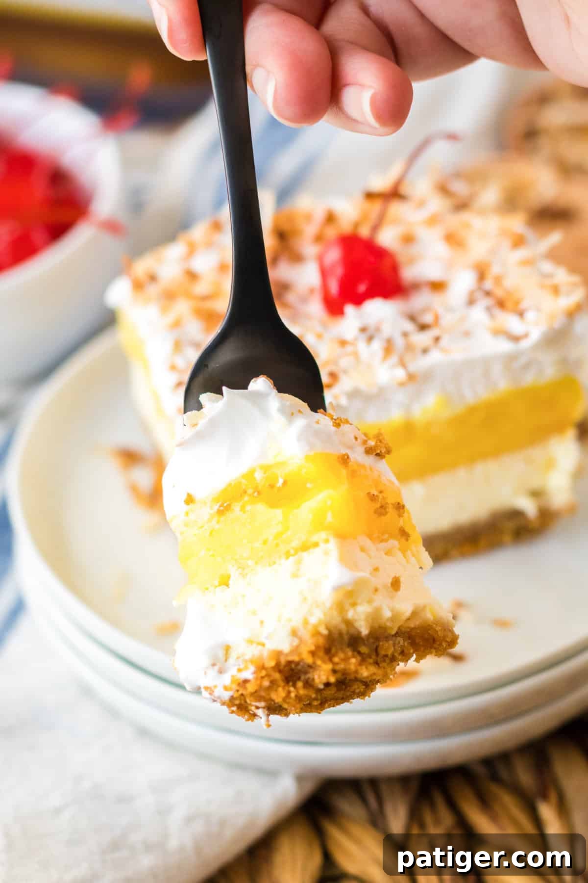 A fork taking a bite from a square of Pina Colada Cheesecake Bar, showing the creamy layers.