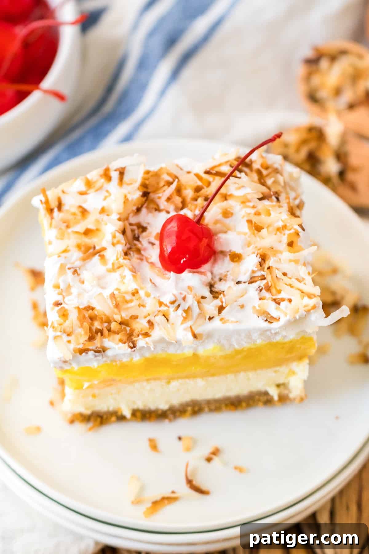 A magnificent layered Pineapple Coconut dessert, showcasing distinct layers of creamy pineapple filling, coconut cheesecake, and fluffy whipped topping, all resting on a rich, buttery graham cracker crust.