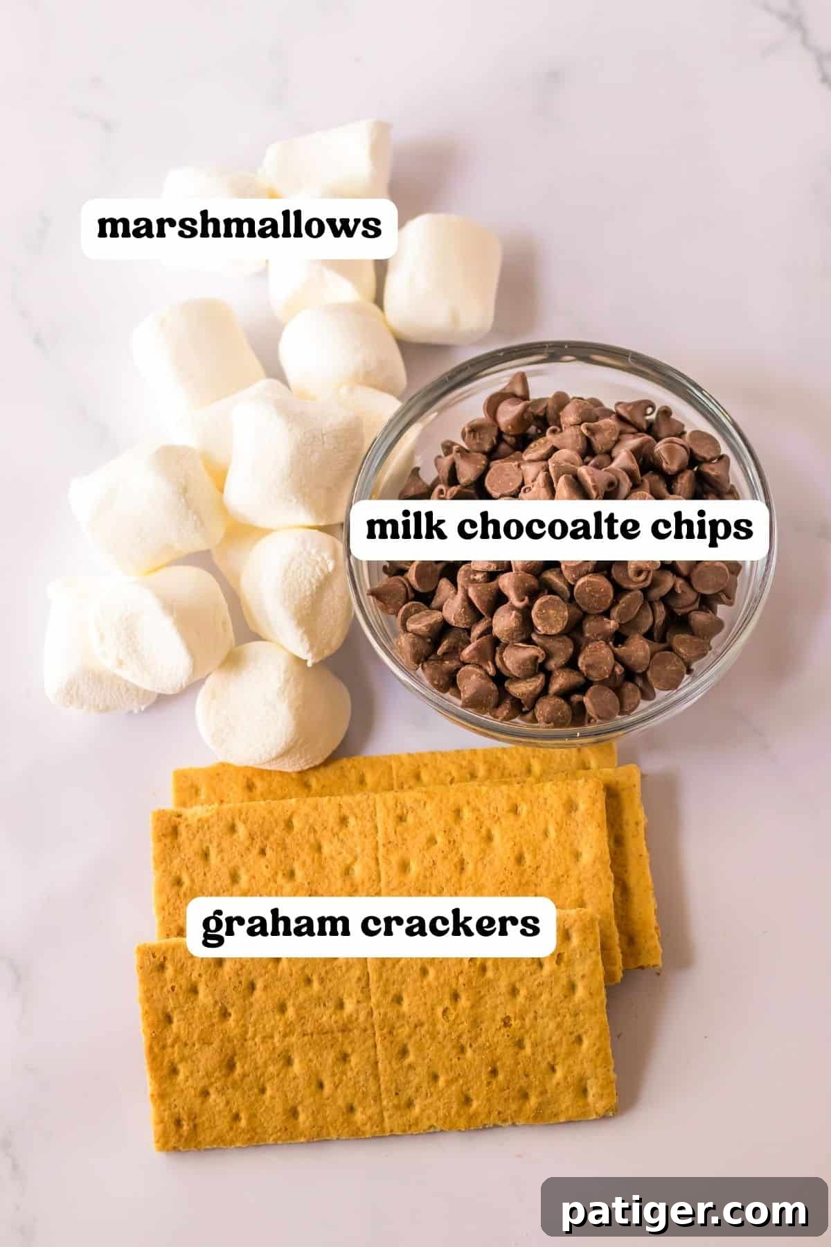 The three essential ingredients for s'mores dip: a bag of marshmallows, a bag of milk chocolate chips, and a stack of graham crackers.
