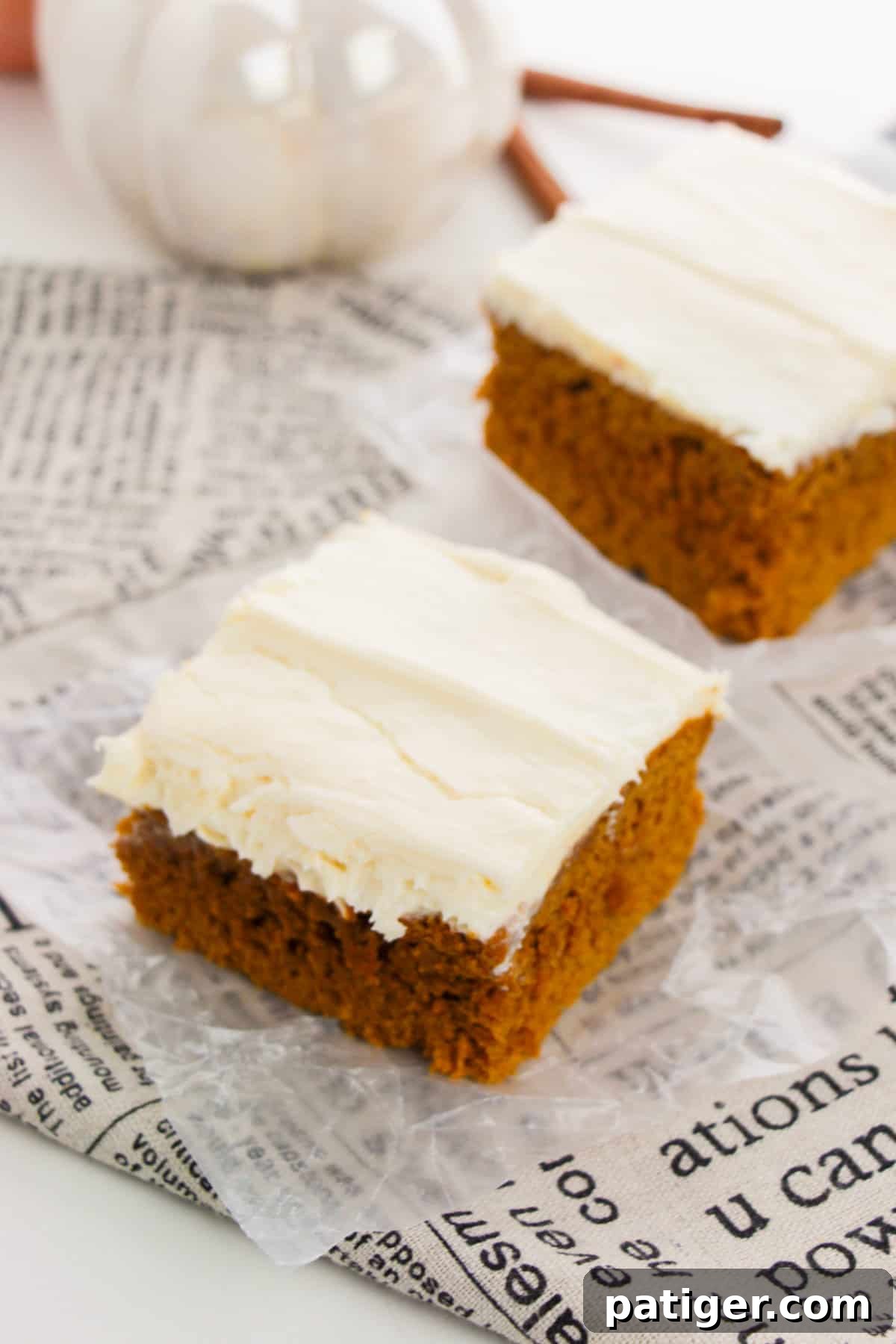 Two slices of moist pumpkin cake made with spice cake mix and pumpkin puree, topped with cream cheese frosting.