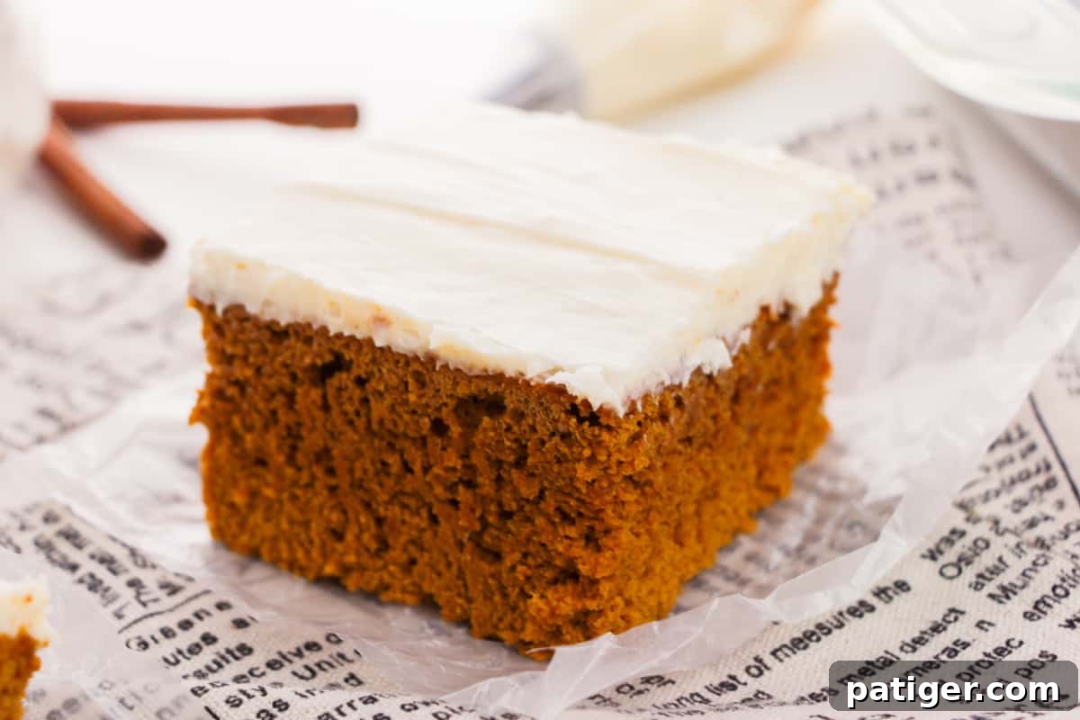 Slice of pumpkin spice cake with a generous dollop of cream cheese frosting.